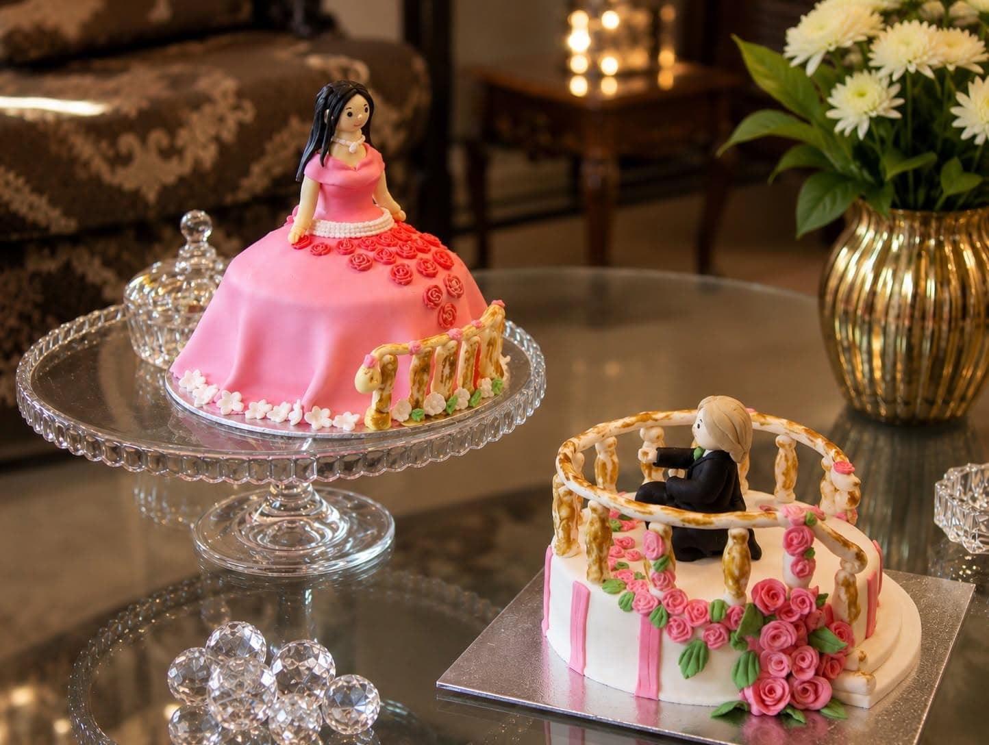A pink doll-shaped cake displayed alongside another pink decorated celebration cake.